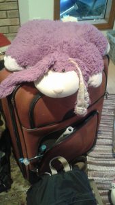 Large suitcase with rabbit pillow pet on top.