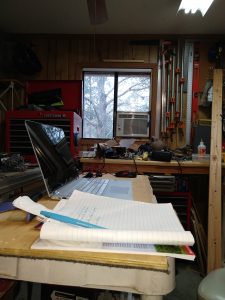 Laptop on a shelf in a crammed-full workshop